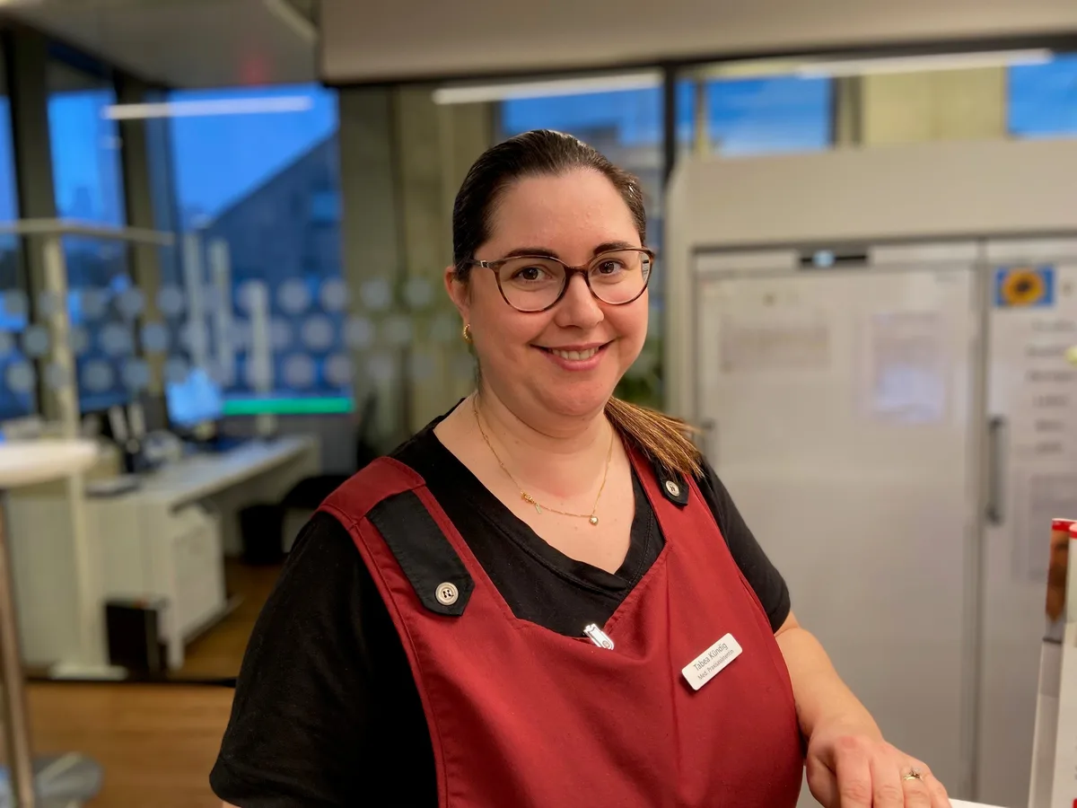 Eine medizinische Praxisassistentin in rotem Kittel am Empfang.